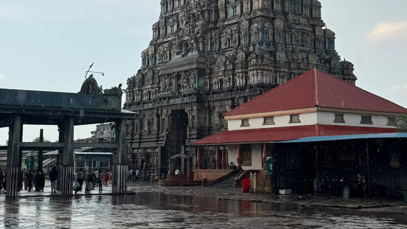 Rain-soaked temple courtyard mirroring a stone gopuram after a monsoon shower in Tamil Nadu