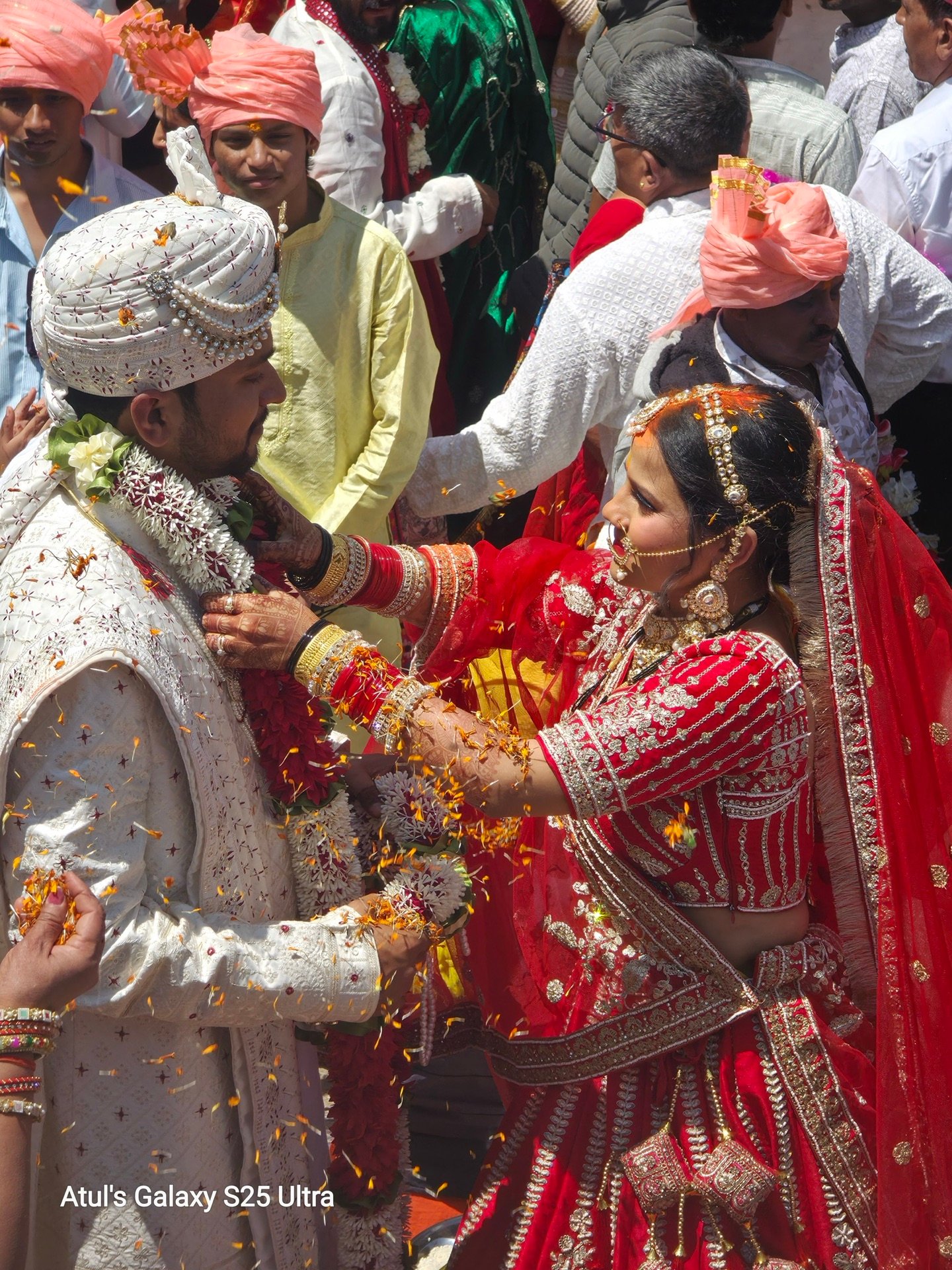 Bride in traditional red attire receiving a flower shower at Triyuginarayan