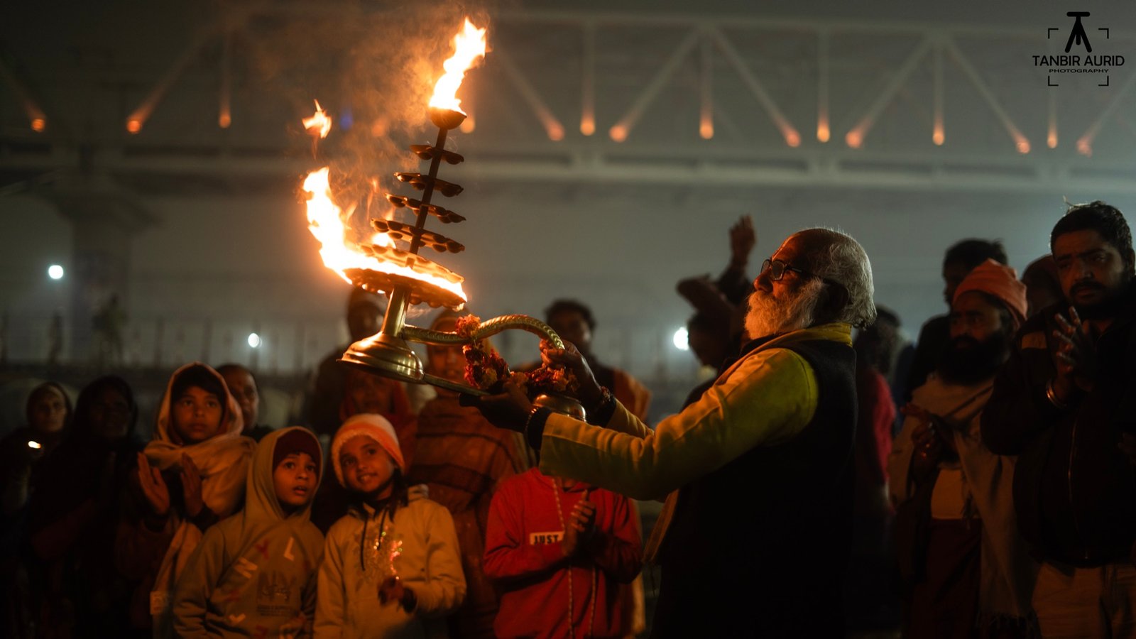 Ganga Aarti at night - a priest holds a multi-tier lamp before a crowd of devotees