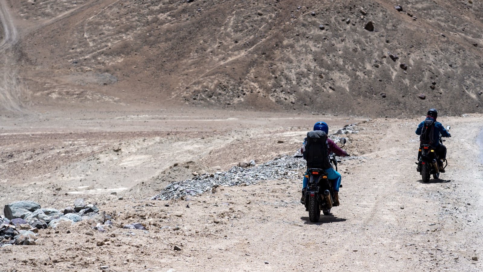 Two motorcyclists on a bare mountain road in Ladakh