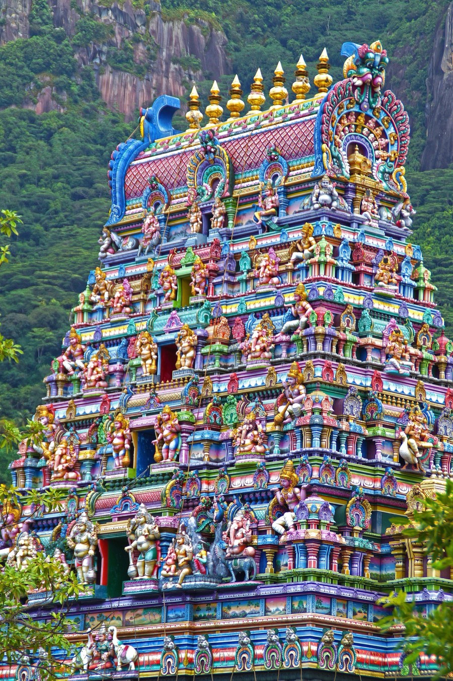 Brightly painted gopuram with a green hillside behind it