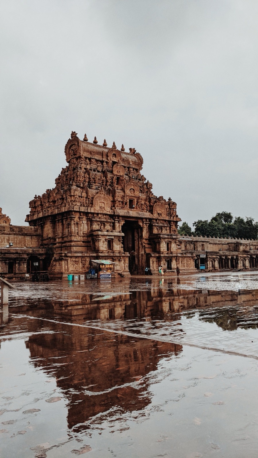 Stone vimana mirrored in monsoon rainwater on the temple courtyard
